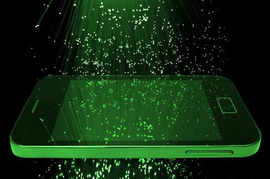 Many illuminated green fiber optic light strands cascading down against a black background and reflecting on the screen of a smart phone in the foreground