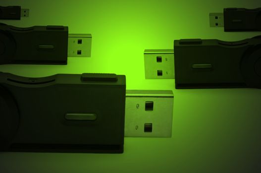 Close and low level capturing several black usb sd adaptors arranged over green light effect filter