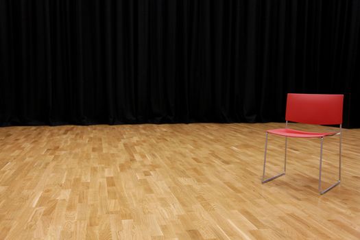 A directors chair on a stage with a blackcurtain in background