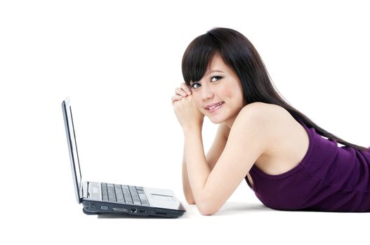 Portrait of an attractive young Asian woman lying on the floor with laptop over white background.