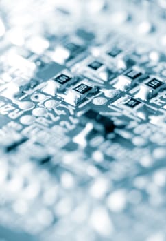 Close-up of electronic circuit board, blue toned, shallow depth of field.