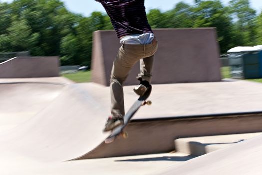 Action shot of a skateboarder skating at the skate park with concrete ramps. Slight motion blur.