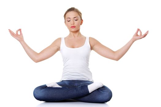 Portrait of young pretty student girl over white background meditating in lotus pose. She is relaxed and concentrated