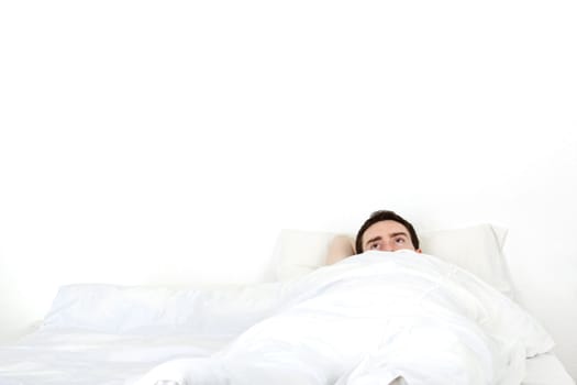 Alone young man in a bed under a white blanket