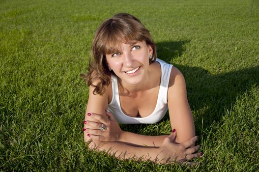 A very beautiful young woman lying down smiling in a field