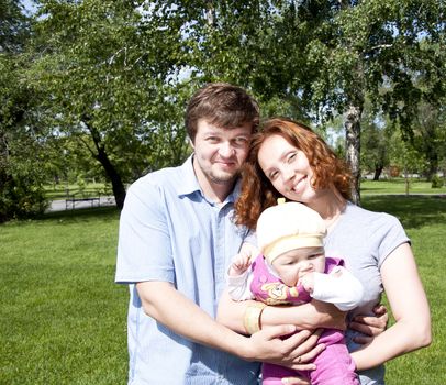 The young family in park, hugs and smile