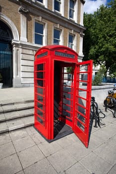Old red phone booth with open door in London