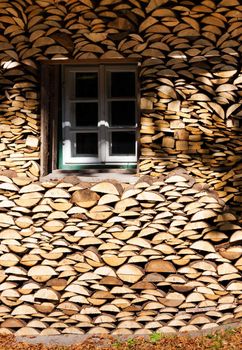 Logs stacked in front of a house facade