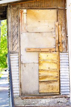 old shaky wooden patio door patched with plywood