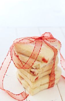 Heart shaped strawberry shortbread cookies wrapped in red ribbon on white background