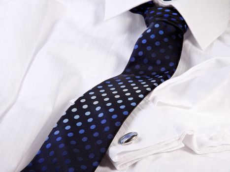 A blue tie and cuff-link on a white shirt