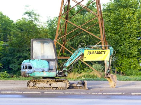 small backhoe on the roadside with the announcement of the scoop