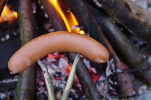 a sausage grilled on a camp fire