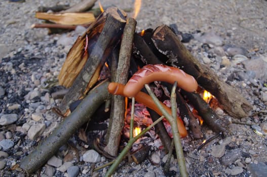 a sausage grilled on a camp fire