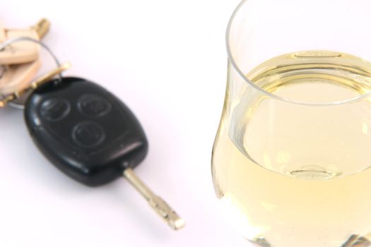 social issues don't drink and drive glass of wine close-up with car keys backgroung blurred on white