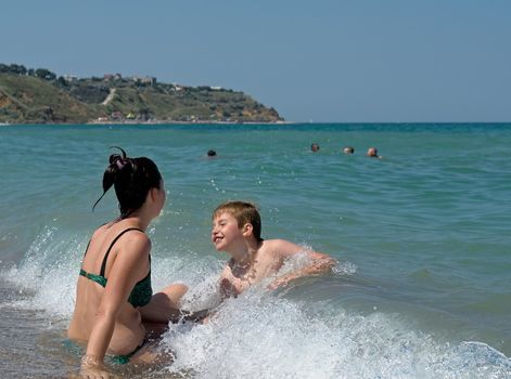 A little boy being held up by his mom after getting his with a rough wave