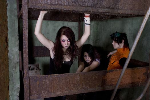 Girls goth in a gloomy cellar in a dirty iron cell