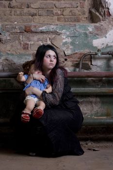 The girl in dark clothes with a doll scaredly looks
