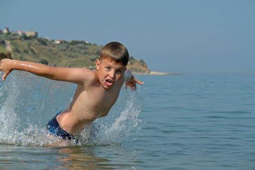 Young boy jumping into wave on a sunny beach