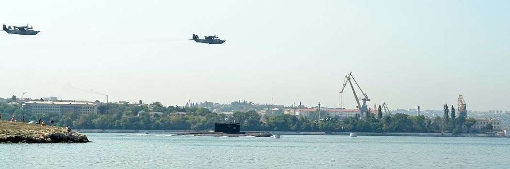 Military planes fly by above a submarine