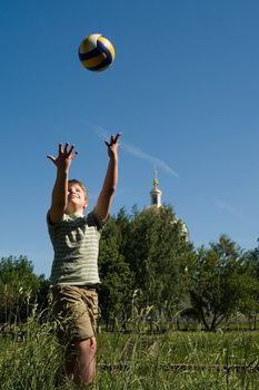 A little boy plays a ball with sky at background 