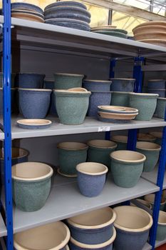 various garden pots for plants and shrubs stacked on shelves in garden centre