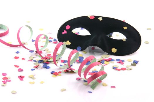 carnival concepts paper confetti streamers and black mask isolated on white background