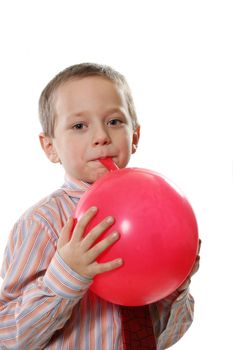 The happy boy inflates a red balloon