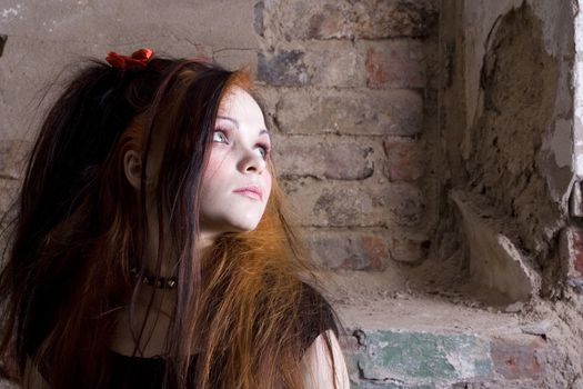 The attractive girl in Gothic style on a background of a brick wall