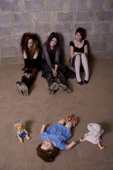 Girls with dolls sit on a floor in depression