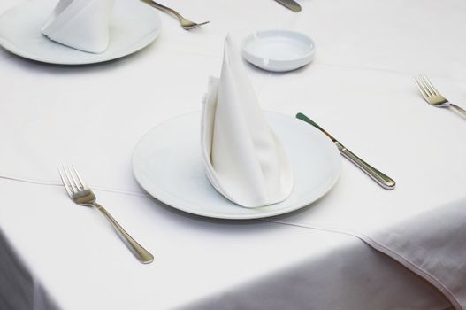 Empty served restaurant table with white tablecloth