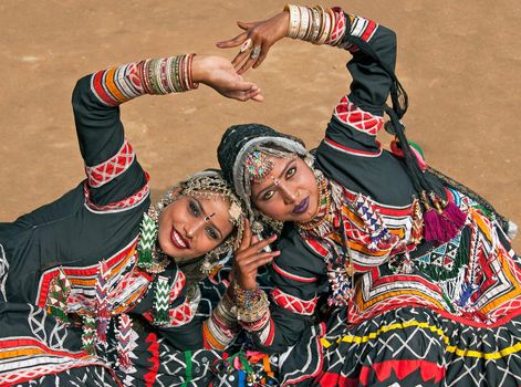 Beautiful Kalbelia dancers in ornate black costumes trimmed with beads and sequins at the annual Sarujkund Fair near Delhi, India.