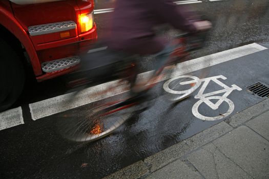 Wet morning traffic with speedy cyclist passing lorry very close.