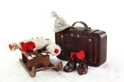 Sled, winter clothes and suitcases in front of white background