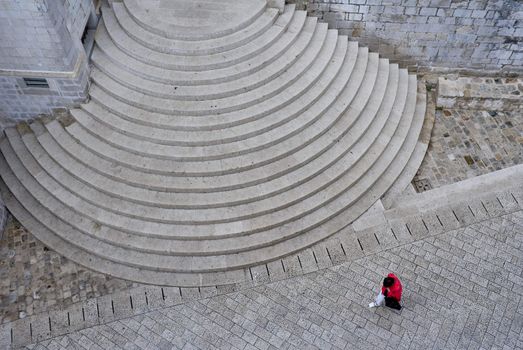 Circular steps to a church and a woman passing by seen from the town wall Dubrovnik, Croatia.