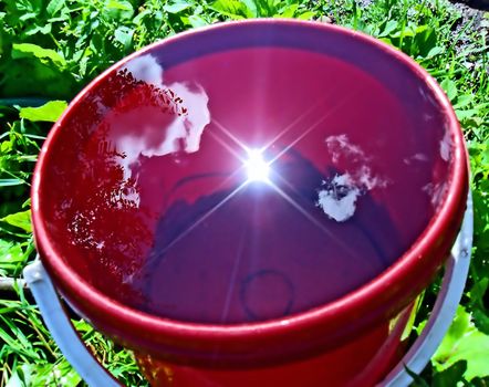 reflection sun in pail with water