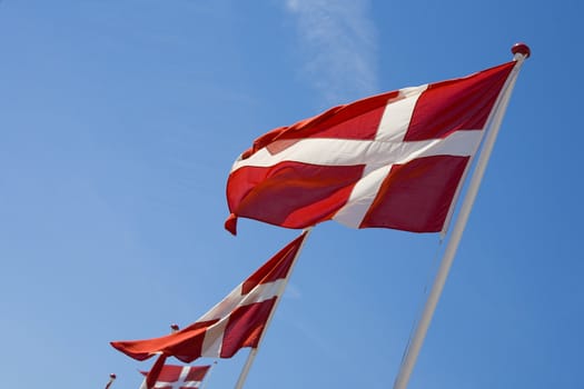 Danish flags waving against the blue summer sky.