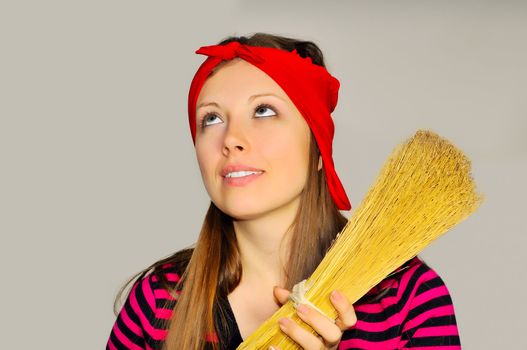 A girl holding a broom and looks up at the ceiling in the apartment