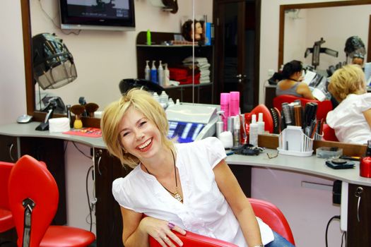 Image of beautiful smiling blondes sitting in red chair