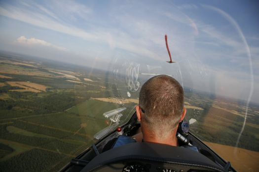 Glider pilot in the air with his plane gliding away in the low evening sun.