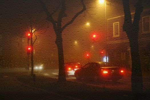 Crossroads in a major city of Denmark a dark rainy night by a traffic light.