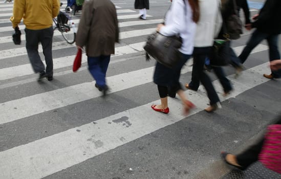 Rush hour in an urban  zebra crossing. Focus on red shoe. With place for text.