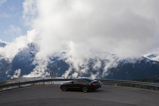 Low hanging clouds behind automobile in a hairpin bend in the Dolomites - Italy.