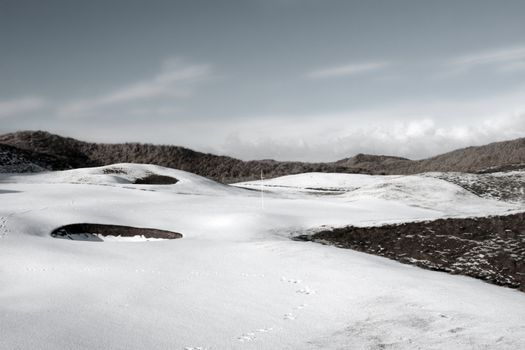 bunkers on a snow covered links golf course in ireland on a grey day in snowy winter weather