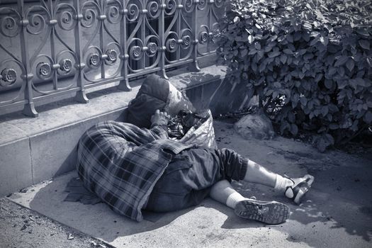 Homeles man sleeping on the pavement near a Metro station - Paris, France at springtime.