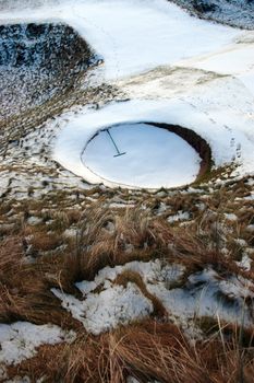 a rake in a bunker on a snow covered links golf course in ireland in snowy winter weather