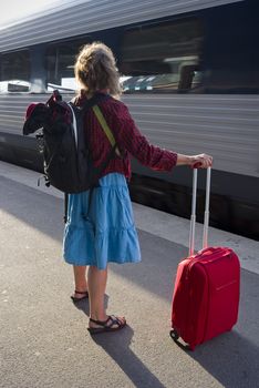 Danish woman with roller bag waiting on the platform for a train.