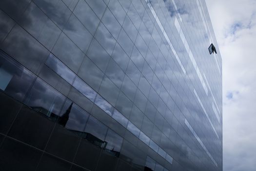 Concept photo. Hope in the middle of the finance crisis. Symbolized by the open window on top of the corporate building. Although the clouds and light are still threatening.