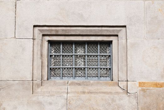 Iron window on the center of aged stone wall
