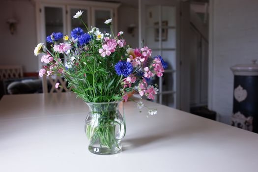 Beautiful spring summer flowers in a glass vase in a living room